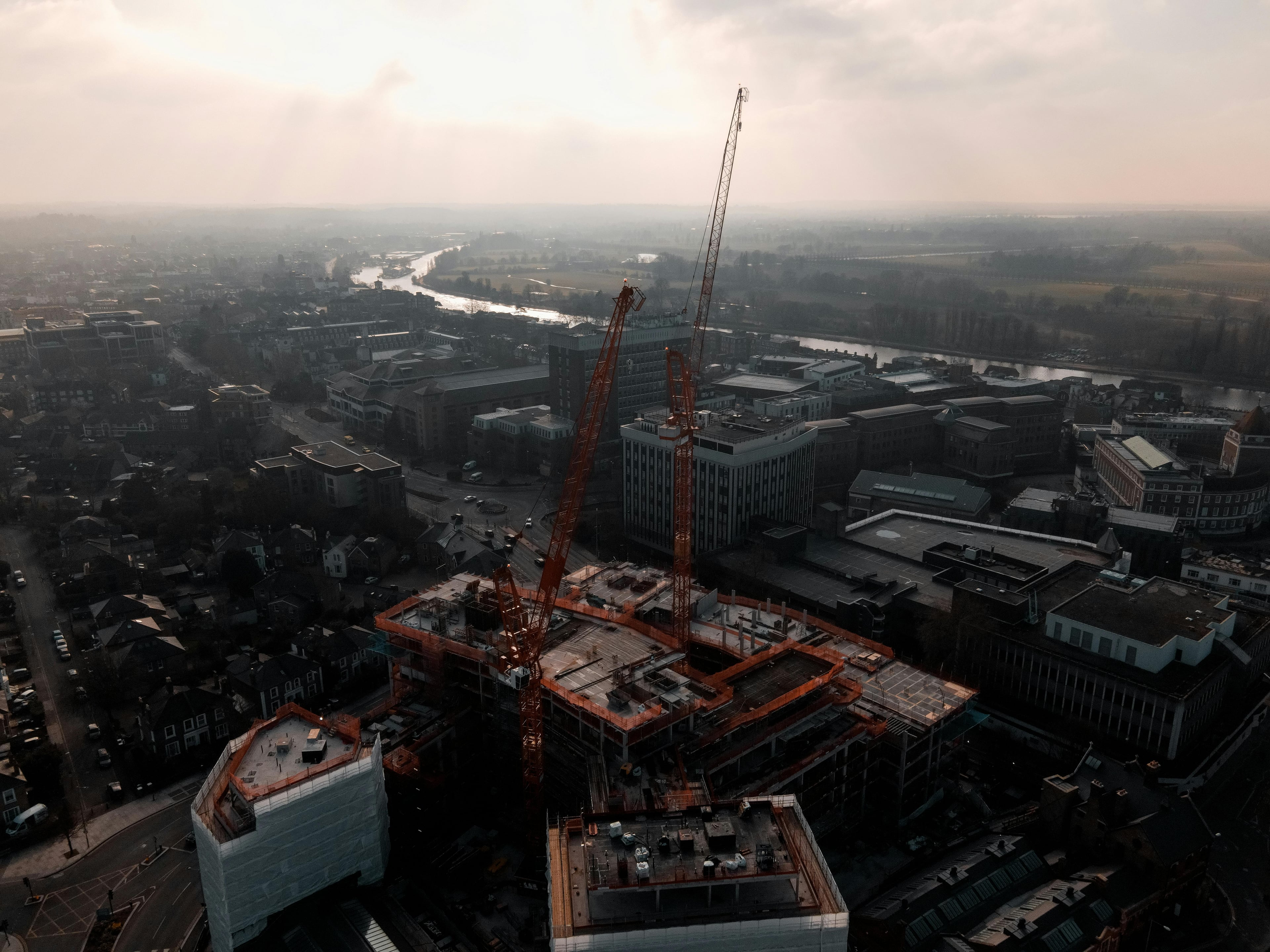 Construction cranes over a cityscape, representing development and progress.